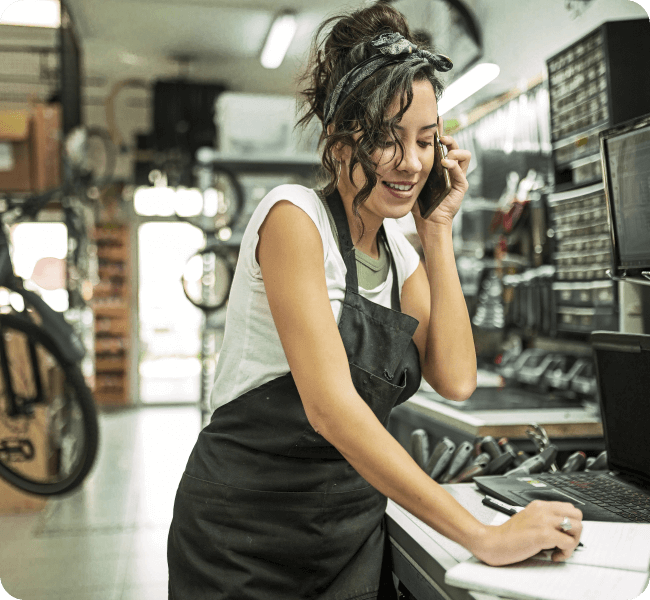 Dark hair millennial female business owner placing call from her bike