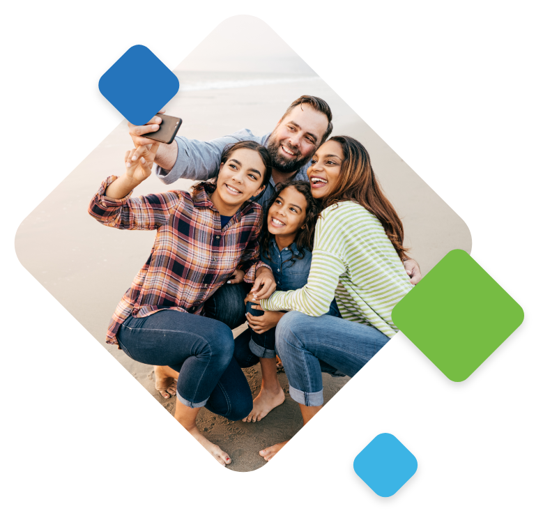 An image of a family of 4, kneeling down on a beach and taking a selfie.