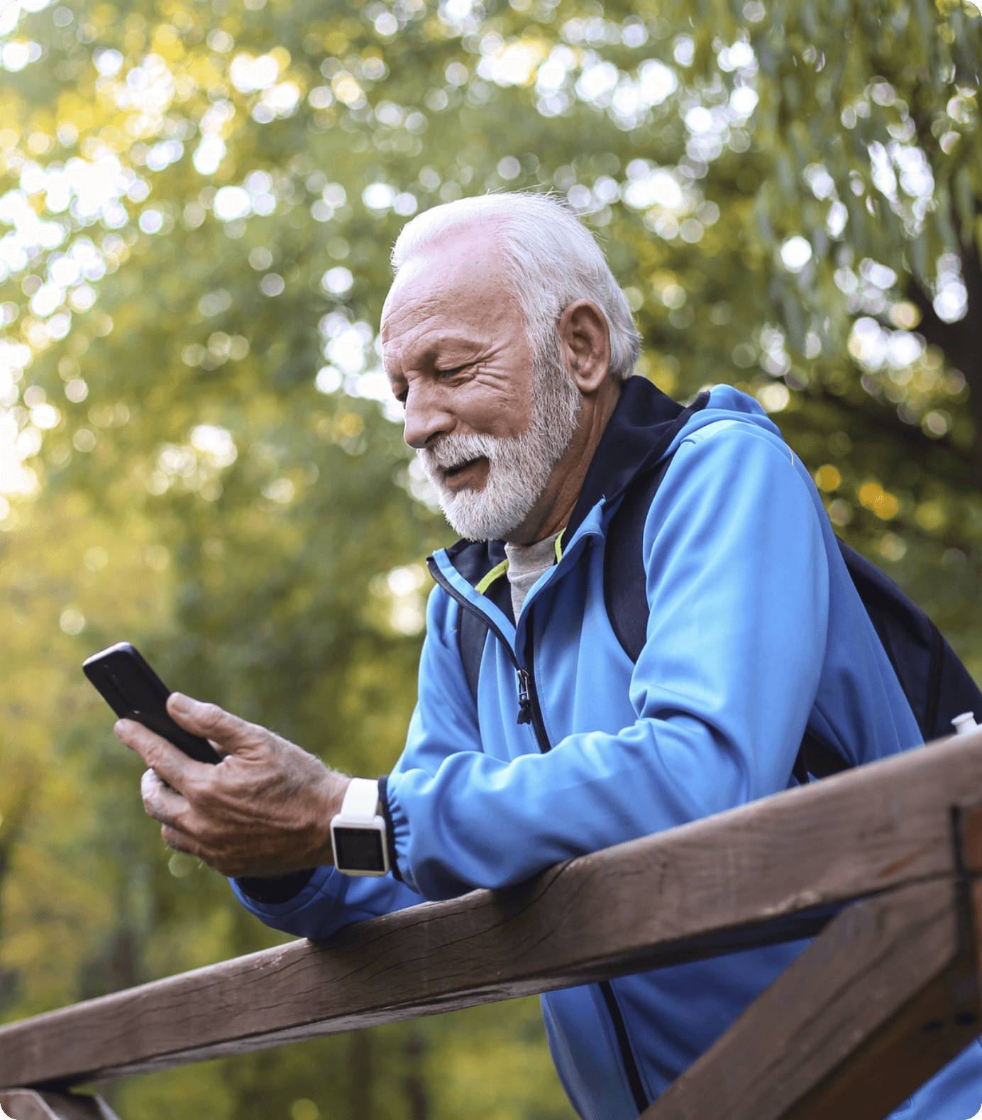 Senior adult male looking at phone on bridge
